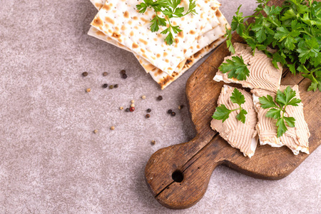 matzah 与自制的肝酱与香菜和洋葱在旧木制切割板上的粗麻布餐巾。灰色大理石背景。复制空间