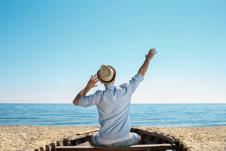 他坐在旧船上举手.照片