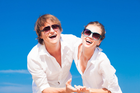 太阳镜中白色的衣服，在户外微笑快乐年轻夫妇的肖像