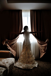 新娘站在他们的婚礼的窗户的剪影