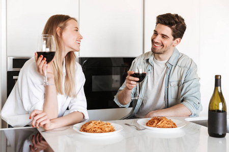 喝的葡萄酒吃意大利面条亚洲情侣吃面条年轻欢快的情侣在厨房的照片