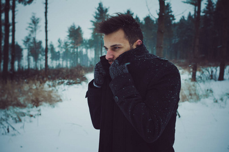 年轻迷人的男人在冬天拥抱雪。特写镜头肖像