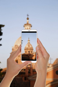 一名游客正在意大利罗马用手机拍摄当晚桑蒂卢卡马蒂娜教堂圆顶的照片