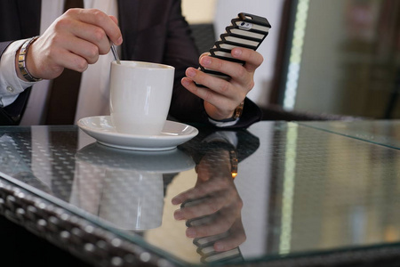 商人坐在一杯咖啡和一个电话在一个黑色的桌子与反射