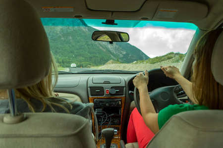 个年轻美丽的女孩开车在阿尔泰的山上行驶, 正沿着蛇形的道路行驶照片