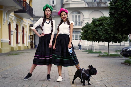 两个年轻的时装模特与可爱的狗摆姿势