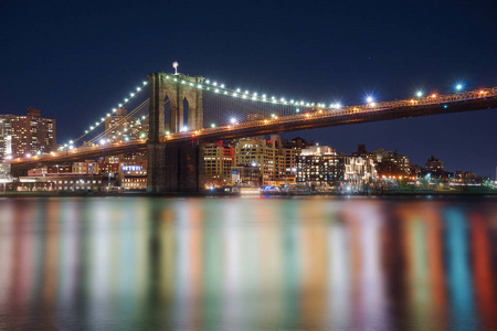 曼哈顿大桥和布鲁克林天际线在河里的美丽模糊的反射在夜间