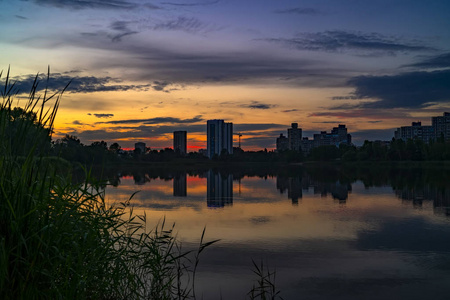 城市日落与城市建筑的剪影在多彩的天空和湖背景