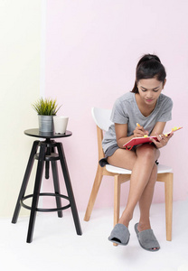 美丽的女士坐在椅子上, 写在书上, 粉彩墙纸