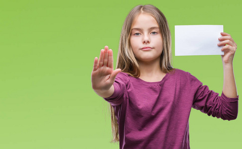 年轻美丽的女孩拿着空白纸卡在孤立的背景与开放的手做停止标志与严肃和自信的表达, 防御姿态