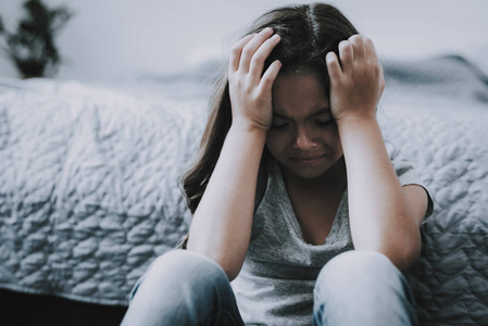 哭闹的小女孩坐在地板上的室内.