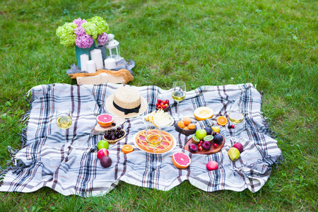 绿色草地上的白葡萄酒和夏日水果的野餐背景在绿色草坪上的左框架上