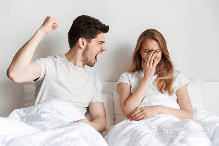 年轻愤怒的男子尖叫的形象他得罪妻子躺在床上争吵