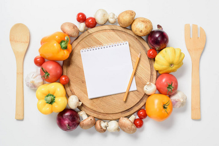 木板, 笔记本和铅笔在白色附近的成熟蔬菜的顶级视图