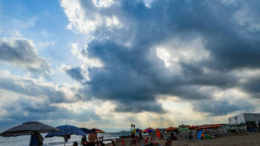 夏日清晨暴风雨过后拥挤的海滩上的云层