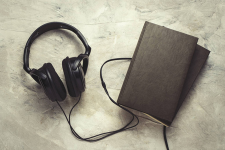 两本书和耳机的白色石材背景。概念电子书
