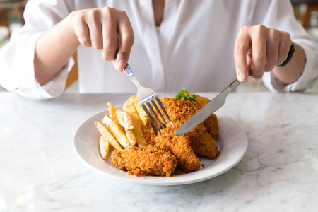 吃炸鸡手用刀叉在餐厅吃薯条和炸鸡的特写图像照片