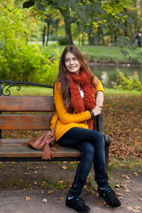 在秋天的公园长凳上的女孩