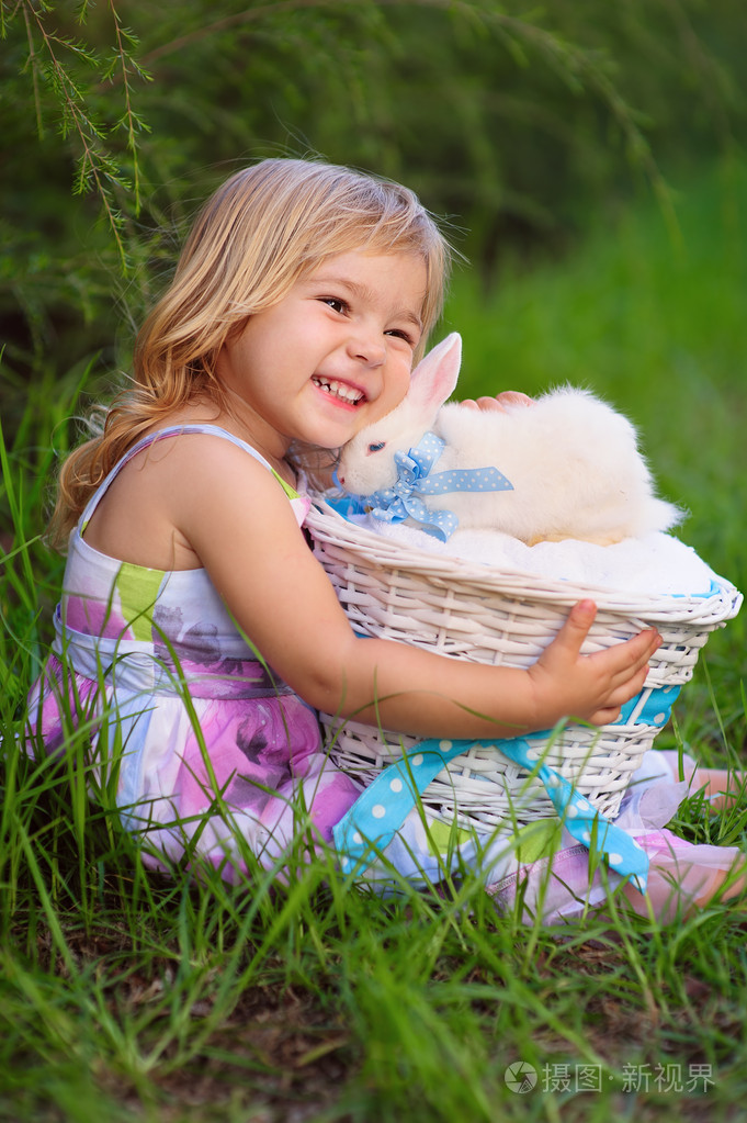 可爱的小女孩与小兔子有一个复活节在绿草