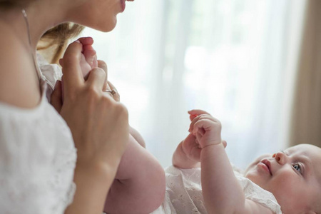 孩子和妈妈在家。母亲抱着她的小孩。新生儿。婴儿脚在母亲的手中。舒适。爱。家庭