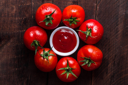 红色, 新鲜的西红柿和番茄酱在一个黑暗的, 木制的背景。顶视图