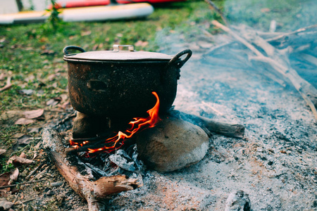 野营和烹饪在野外条件下, 在篝火上煮沸的锅在早晨野餐.