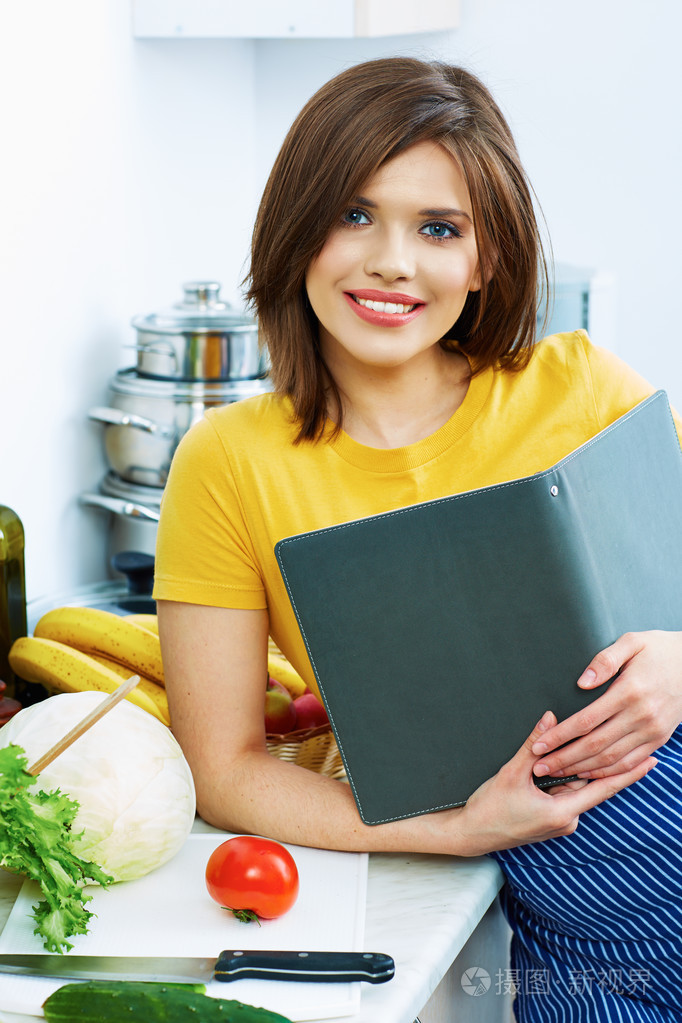 烹饪的女人站在厨房里,芦苇食谱从菜单中