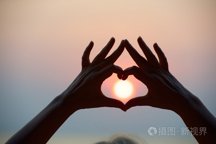心的形状使手和海上日落