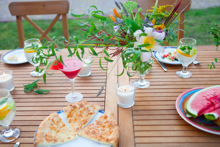 家庭户外晚餐在花园里的夏季日落。野餐食品和饮料概念