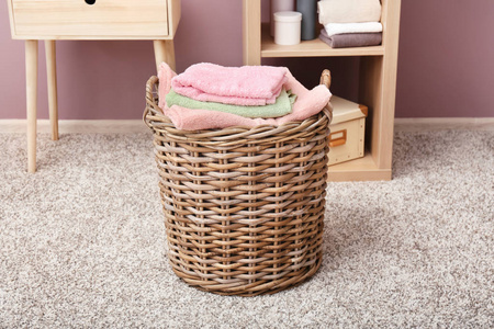 在浴室地板上折叠干净的毛巾柳条篮