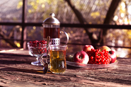 秋天静止不动的生活与茶杯茶杯茶杯和模糊的树木在背景。木桌上的一杯茶和苹果
