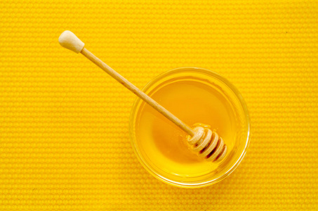 蜂蜜在黄蜂蜡背景下的蜂蜜勺图片