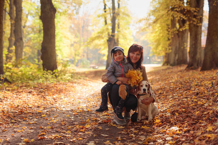快乐的年轻祖母与孙女和狗。中年妇女与小女孩和猎犬散步户外在秋季公园