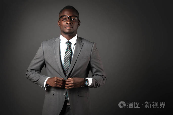 严肃的黑人年轻人, 戴着眼镜, 穿着灰色西装.情感商业肖像