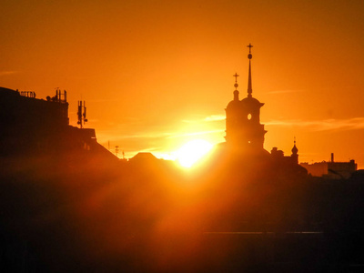 太阳躲在城市教堂的圆顶后面。日落城市景观