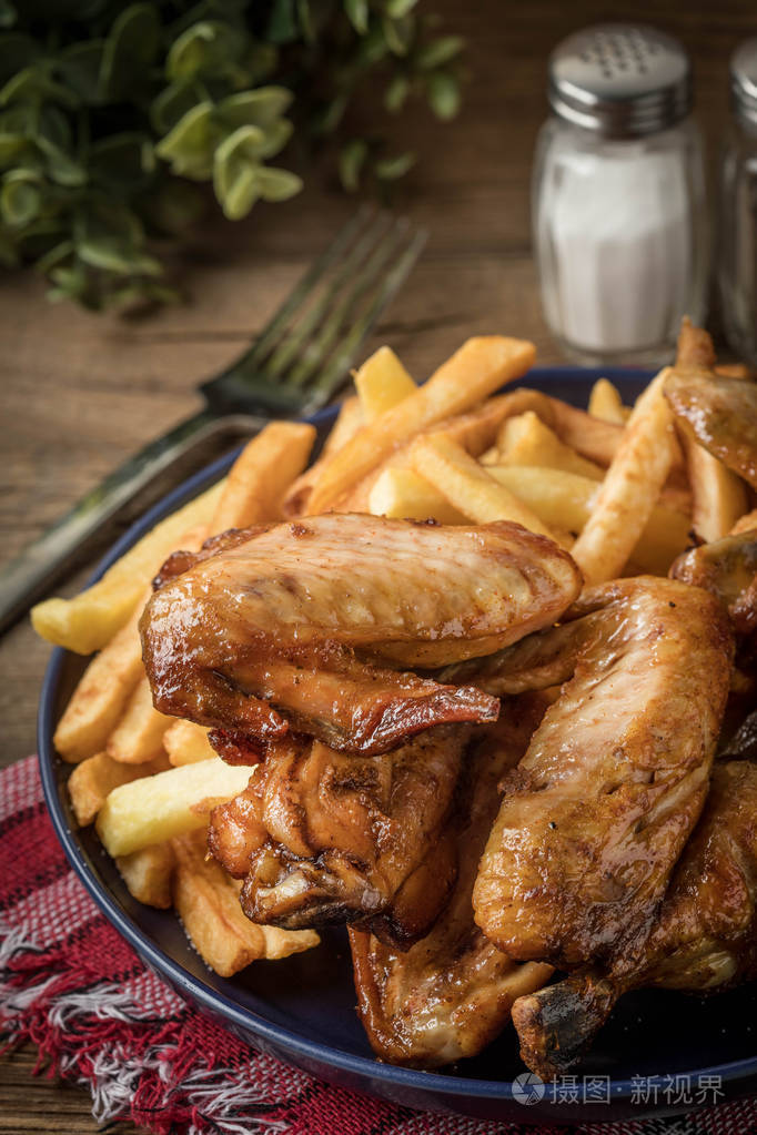 烤的鸡翅配薯条木制的桌子上