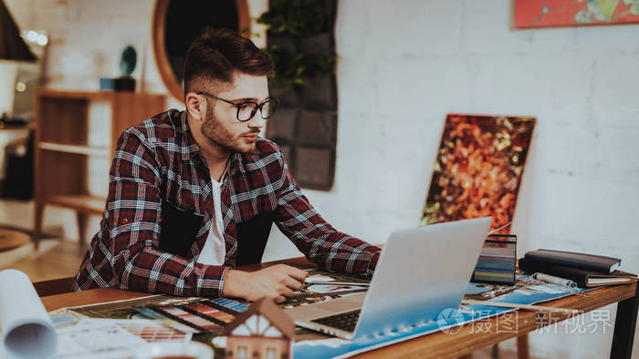 年轻的平面设计师的肖像工作在笔记本电脑室内带着眼镜坐在工作场所做