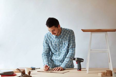 木匠用铅笔在桌子上用工具制作选秀计划