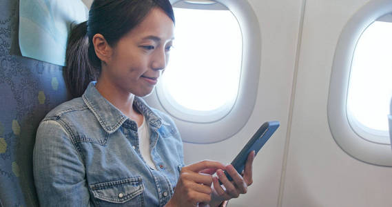 在飞机上使用手机的妇女