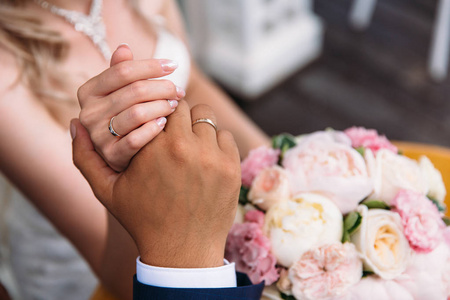 结婚日的爱的人, 新婚夫妇轻轻握住手, 特写裁剪框架。结婚戒指, 新娘花束