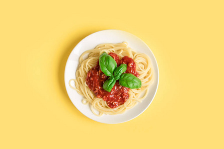 意大利面条肉酱在黄色背景, 顶部视图。番茄酱和罗勒面食盘在创意黄色背景下