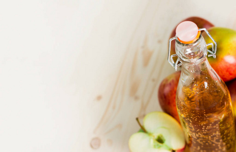 一瓶新鲜苹果汁和半苹果在秋天苹果附近。木质背景, 文字空间, 从上面查看