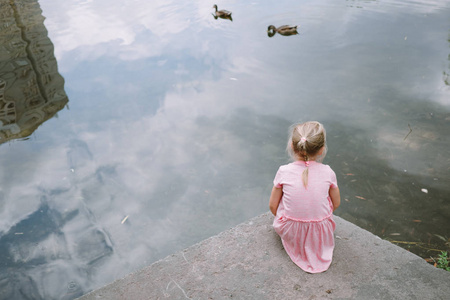 可爱的小女孩坐在河岸的肖像
