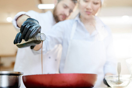 关闭两个专业厨师工作在餐厅厨房钻研酱油到煎锅, 关注前景, 复制空间