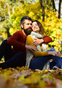 夫妇在爱与围巾坐在叶子在公园