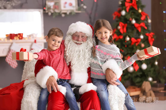孩子们的礼物盒坐在正宗的圣诞老人的膝盖室内
