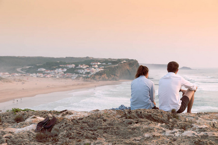 一对年轻夫妇在蒙 Clerigo 海滩前观看日落附近的悬崖