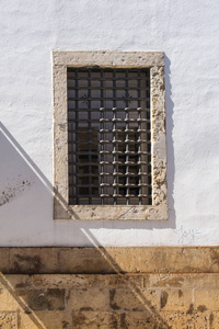 建筑的白色外立面, 带有光栅和石头框架的大窗户。墙的石褐色底座。对角线阴影。里斯本, 葡萄牙