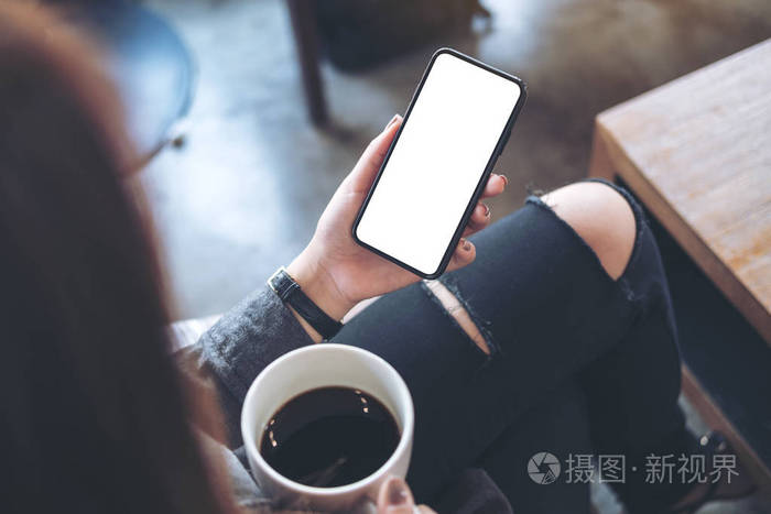 在咖啡馆里喝咖啡时一个女人坐在交叉腿上手持黑色手机大腿上空白的