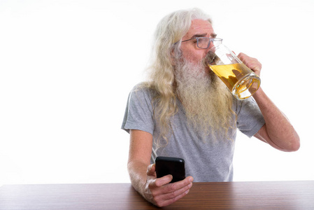 手持手机和饮料的高级胡子男子摄影棚拍摄
